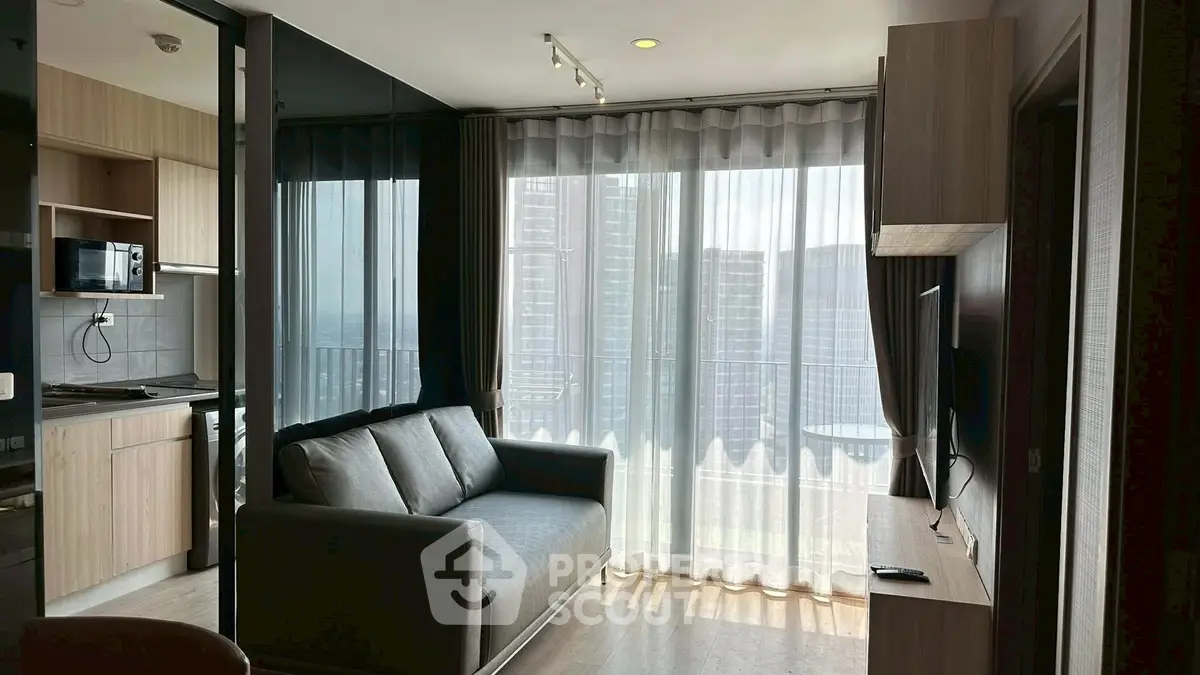 Modern living room with large windows and kitchen view in a stylish apartment.