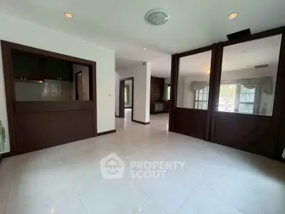 Spacious open-plan living area with large windows and elegant wooden accents.