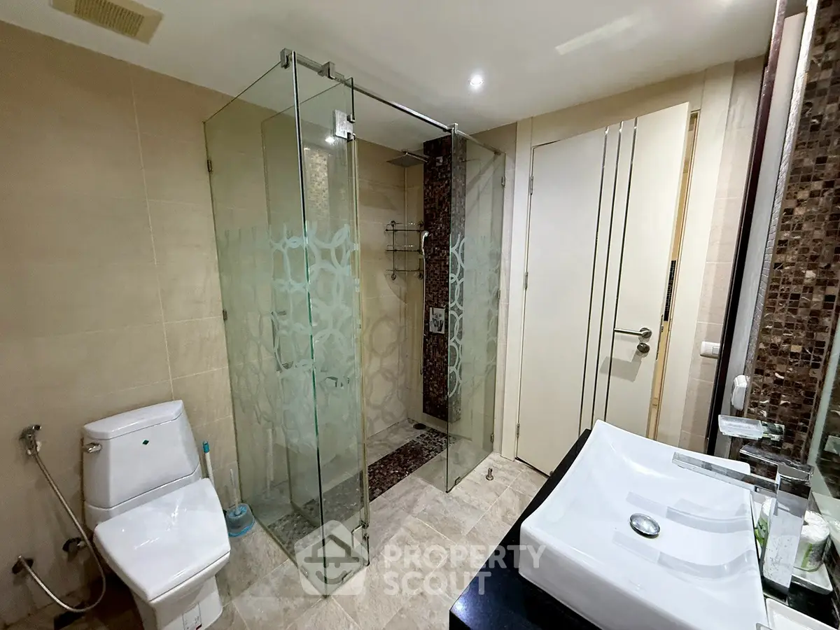 Modern bathroom with glass shower and stylish sink in luxury home.