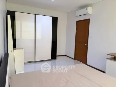 Modern bedroom with sleek wardrobe and air conditioning in a minimalist design.