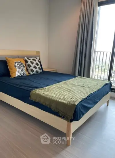 Modern bedroom with stylish decor and large window offering natural light.