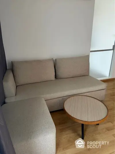 Modern living room with cozy beige sofa and wooden coffee table on hardwood floor.