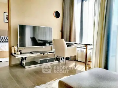 Modern living room with sleek furniture and large TV, featuring natural light from floor-to-ceiling windows.