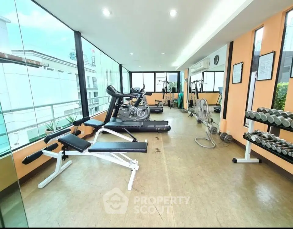 Spacious gym with modern equipment and large windows offering city views