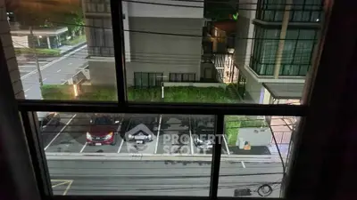View from window overlooking parking area and modern building exterior at night.