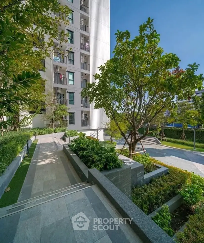 Modern apartment building with lush green garden and pathway