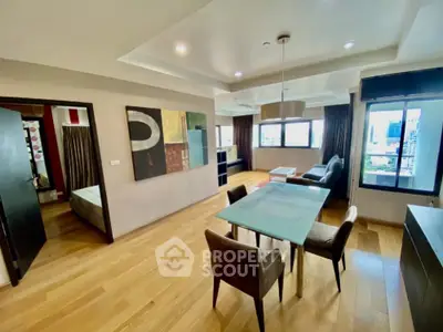 Modern open-plan living room with dining area and city view, featuring stylish decor and ample natural light.