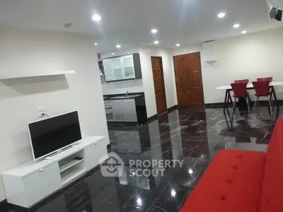 Modern open-plan living room with sleek black flooring and stylish red accents.