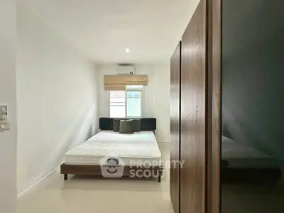 Modern minimalist bedroom with natural light and sleek furnishings.