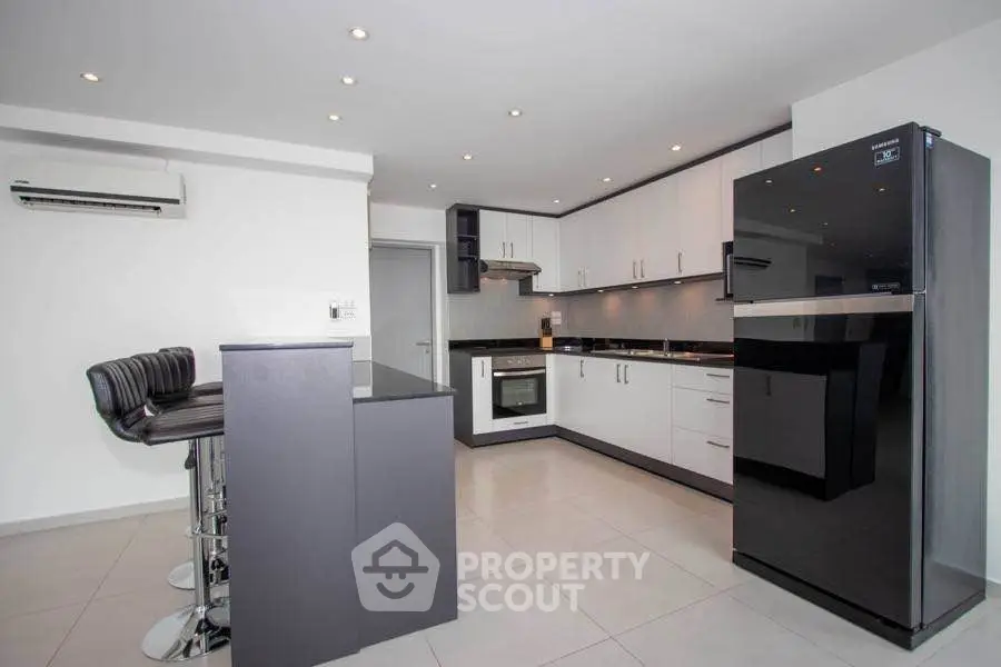 Modern kitchen with sleek black and white design, featuring an island and stainless steel appliances.