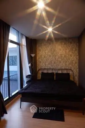 Cozy bedroom with modern decor and large windows offering natural light.