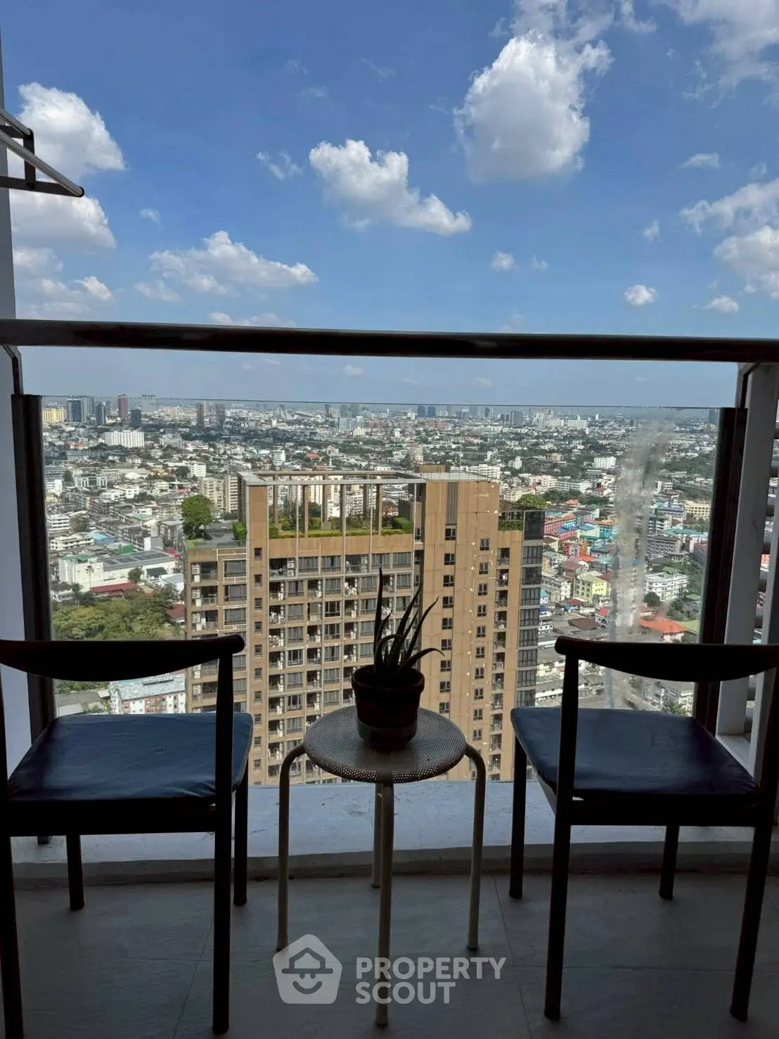 Stunning cityscape view from a high-rise balcony with seating area.