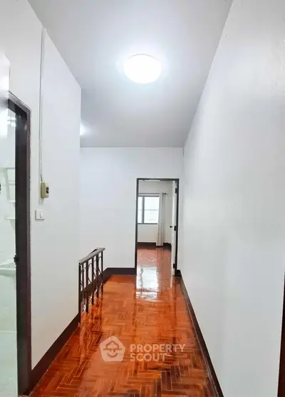Bright hallway with polished wooden floors and white walls in a modern home.