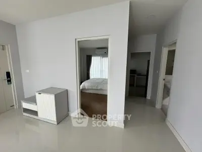 Spacious modern apartment interior with bedroom and bathroom view, featuring sleek white walls and glossy flooring.