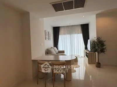 Modern living room with elegant decor and natural light, featuring a cozy seating area and stylish dining setup.