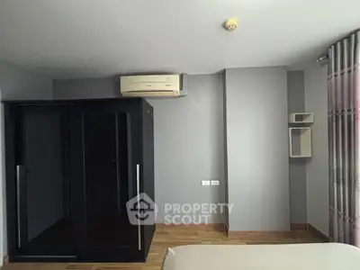 Modern bedroom with sleek black wardrobe and air conditioning unit