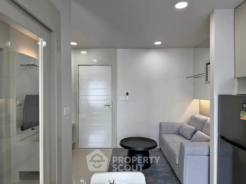 Modern living room with sleek gray sofa and stylish black coffee table in a compact apartment.