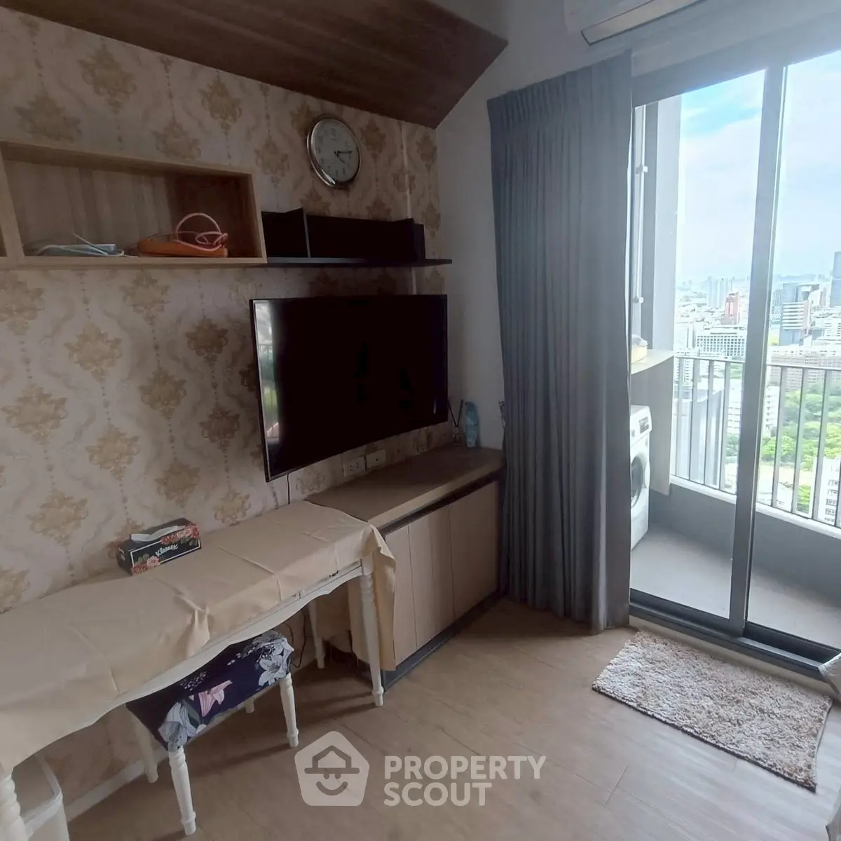 Cozy living room with TV, balcony view, and washing machine in modern apartment.