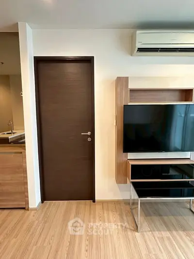Modern living room with sleek TV stand and air conditioning unit, featuring wooden flooring and neutral tones.