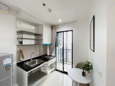 Modern kitchen with balcony view, sleek countertops, and open layout in a bright apartment.