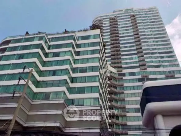 Modern high-rise building with glass facade and unique architectural design.