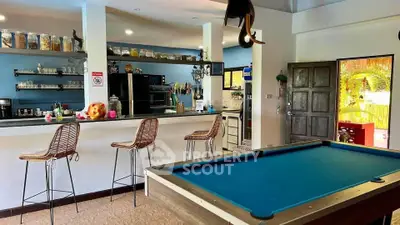 Spacious open-plan kitchen with bar seating and pool table, perfect for entertaining.