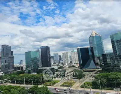 Stunning cityscape view of modern skyscrapers and lush greenery under a vibrant blue sky.