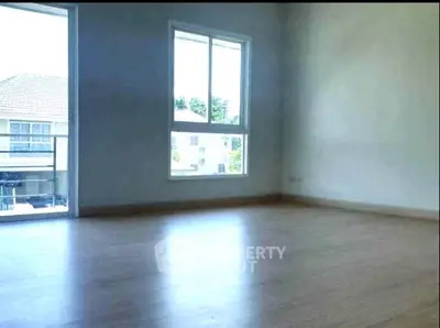 Spacious empty room with large window and wooden flooring in modern home