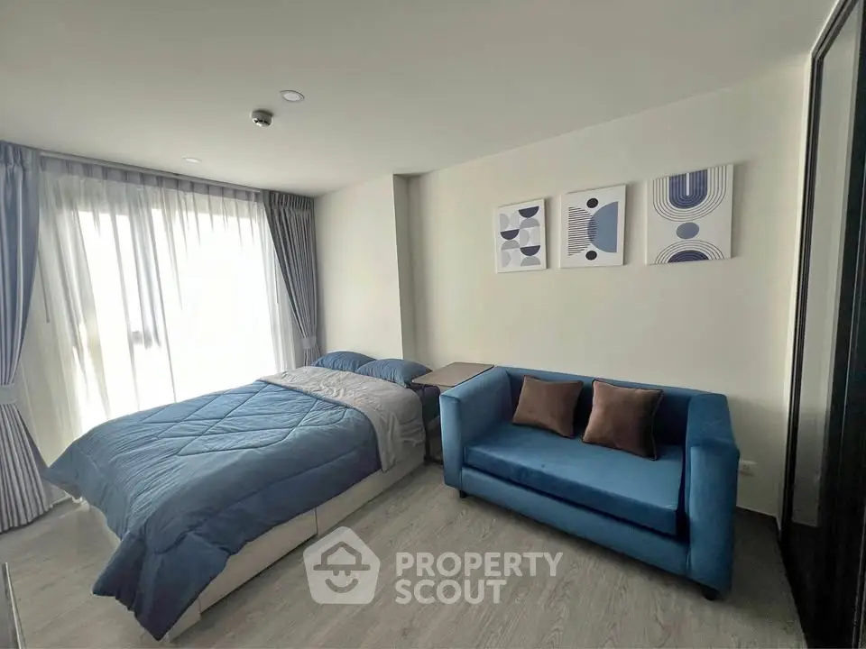 Modern bedroom with cozy blue sofa and stylish decor in a bright apartment.