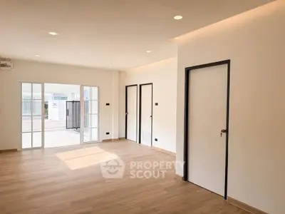 Spacious modern living room with wooden flooring and large windows for natural light.