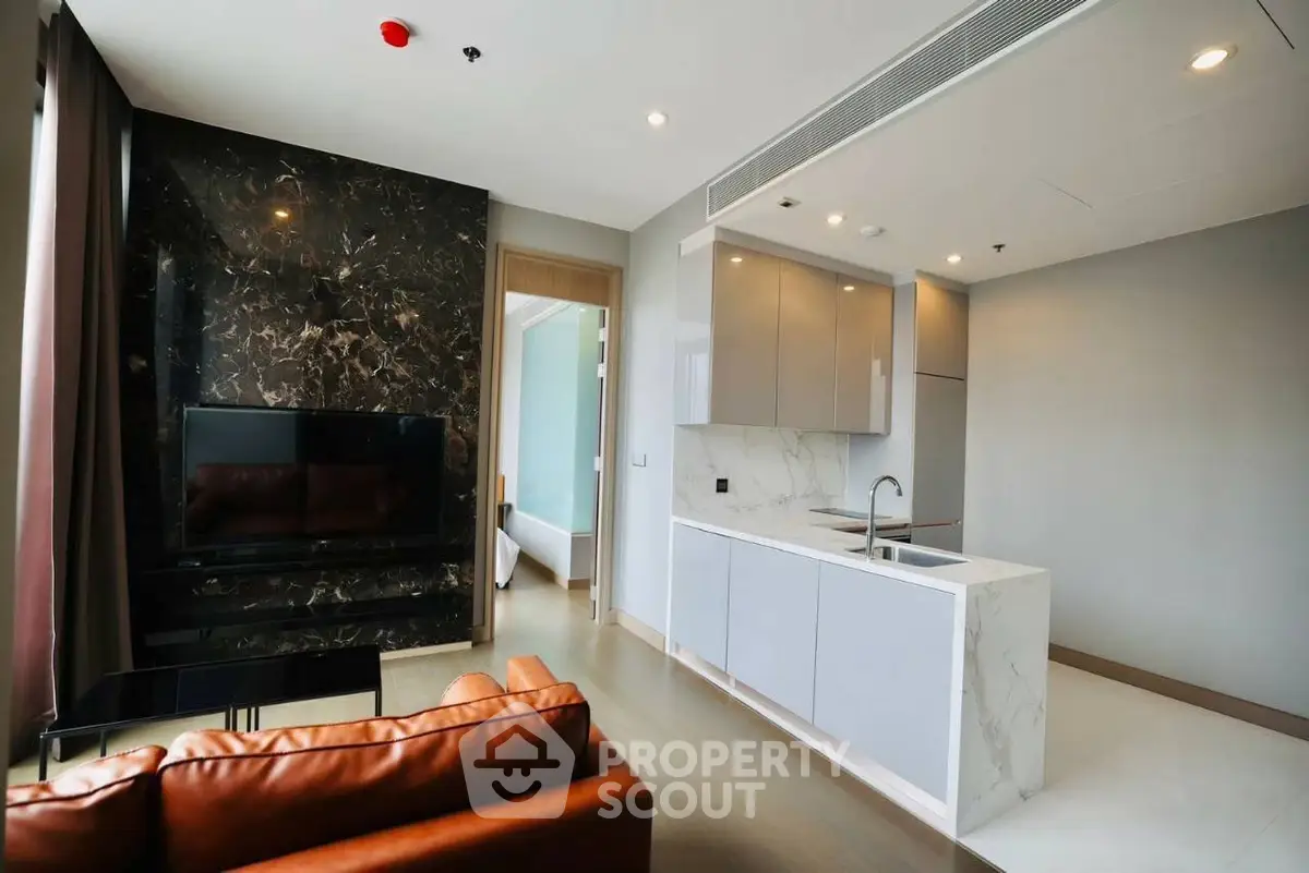 Modern open-plan living room with sleek kitchen and marble accents