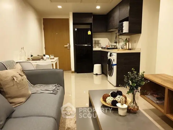 Modern living room with integrated kitchen featuring sleek appliances and cozy decor.