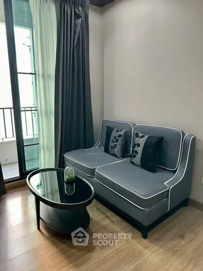 Stylish living room with modern gray sofa and glass coffee table near balcony
