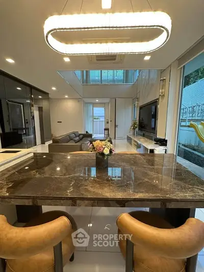Luxurious open-plan living room with elegant marble dining table and modern lighting