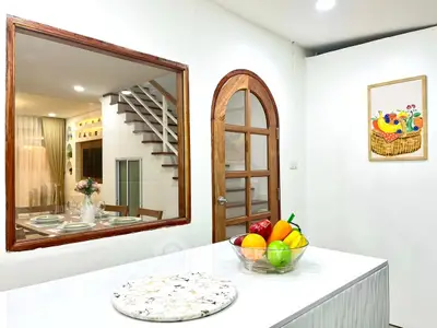 Modern kitchen with open layout and stylish decor, featuring a fruit bowl and elegant dining area view.