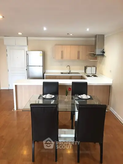 Modern kitchen with dining area, featuring sleek appliances and wooden flooring for a cozy home atmosphere.