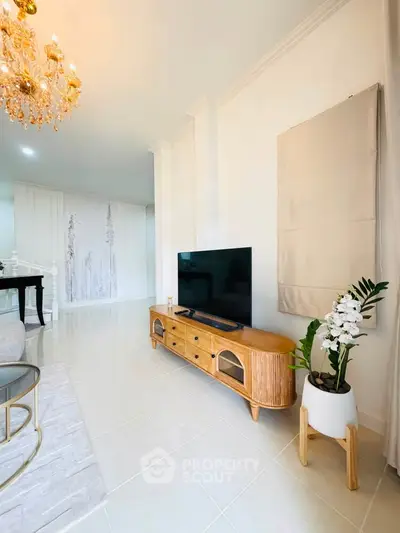 Elegant living room with modern TV stand and chandelier, showcasing stylish interior design.