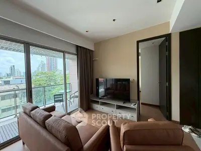Spacious living room with large windows and balcony offering city views, perfect for urban living.