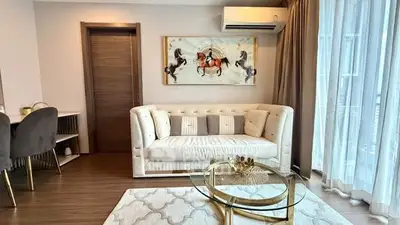 Elegant living room with stylish decor, featuring a plush sofa, modern artwork, and large window for natural light.