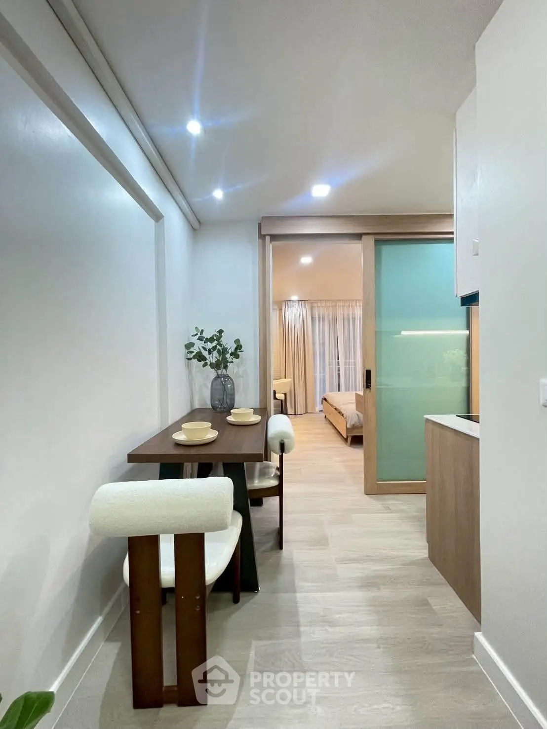 Modern apartment hallway leading to a cozy bedroom with stylish decor and ambient lighting.