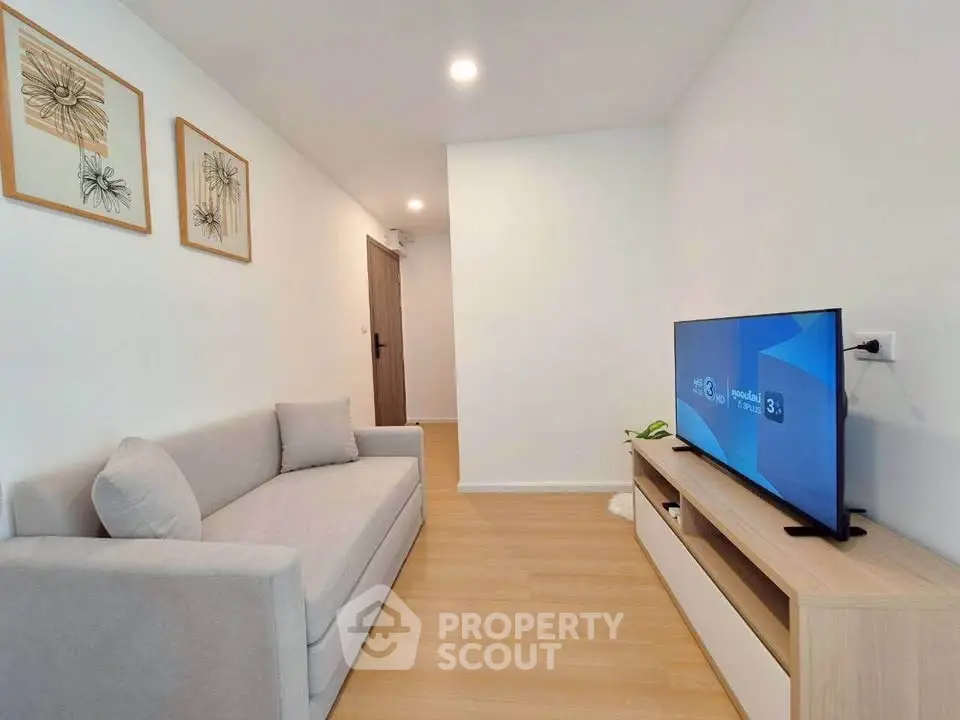 Modern living room with sleek TV setup and cozy sofa in a minimalist apartment.