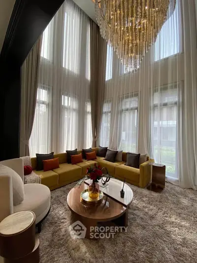 Luxurious living room with high ceilings, elegant chandelier, and plush seating in a modern home.