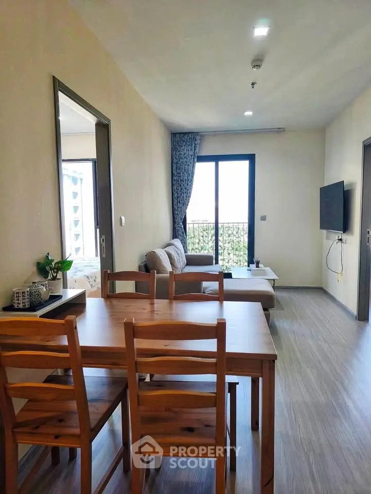 Spacious modern living room with wooden dining set and cozy seating area, featuring large window for natural light.