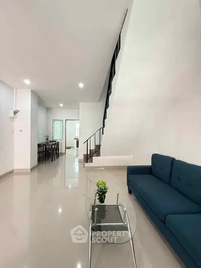 Modern living room with sleek staircase and stylish blue sofa
