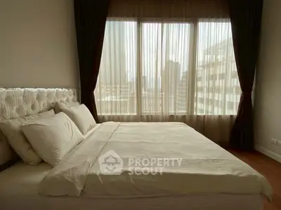 Cozy bedroom with large window offering city view, perfect for relaxation.