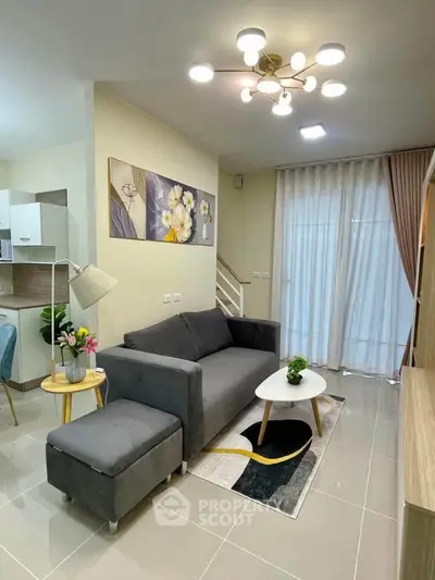 Modern living room with stylish decor and natural light, featuring a cozy gray sofa and elegant lighting.