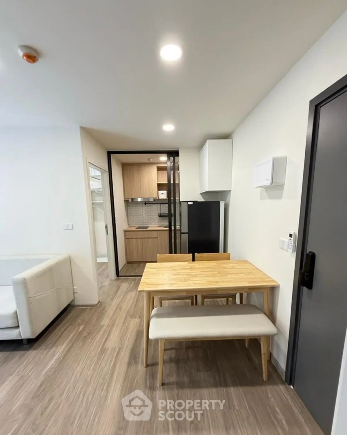 Modern apartment dining area with wooden table and kitchen view