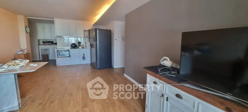 Spacious open-plan living room with modern kitchen and sleek wooden flooring.
