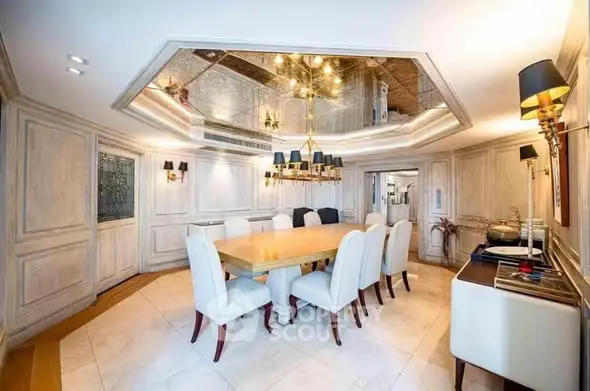 Luxurious dining room with elegant chandelier and mirrored ceiling in upscale home.