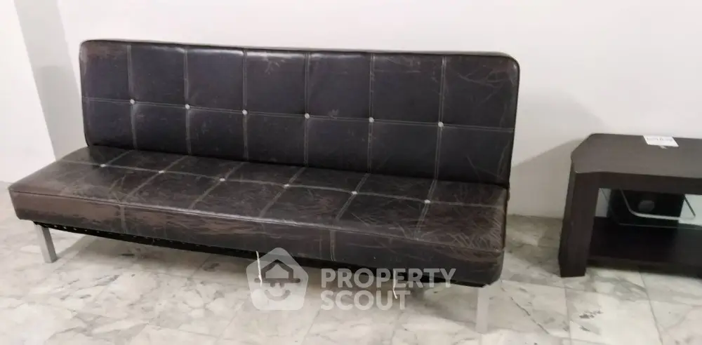 Modern minimalist living room with sleek leather sofa and marble flooring.